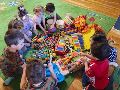 Children playing with musical toys on a green carpet.