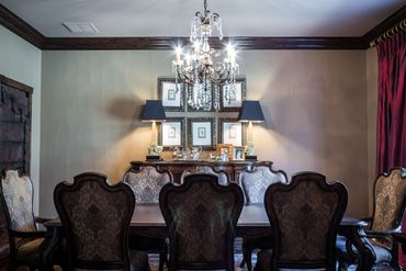 A dining area with a chandelier and classic, regal-looking chairs