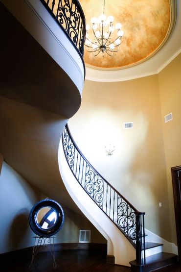 Close-up of the curved staircase by the entrance, an elegant chandelier above it