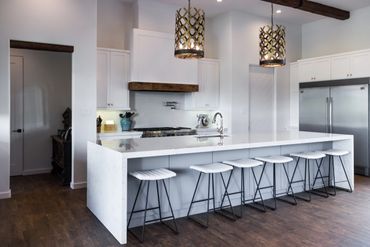 A white kitchen with modern chairs beside the counter