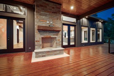 An outdoor fireplace between the glass doors and windows