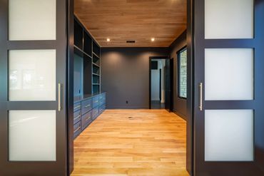 A black-walled home office with light wood floors