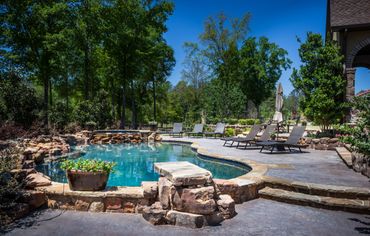 An outdoor pool with rock trims and a stone floor