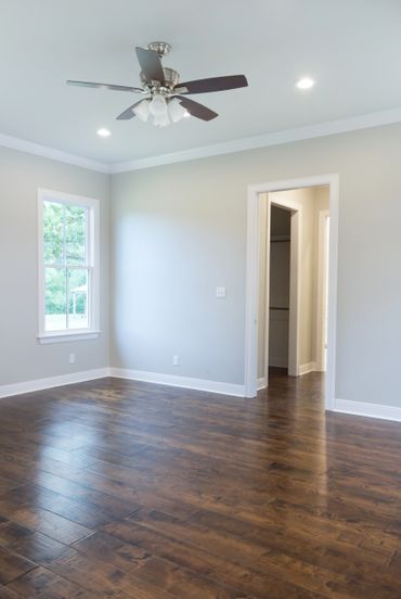 An empty room with wooden floors, white walls, and a window