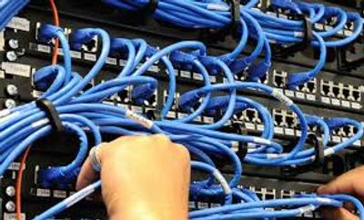 Hands managing numerous blue network cables on a server rack.