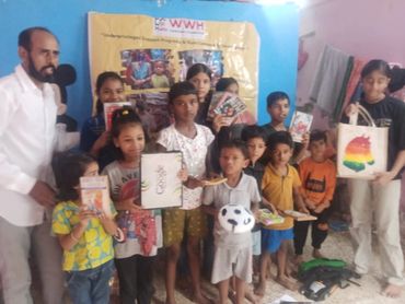 Group of children and adults holding books and crafts indoors.