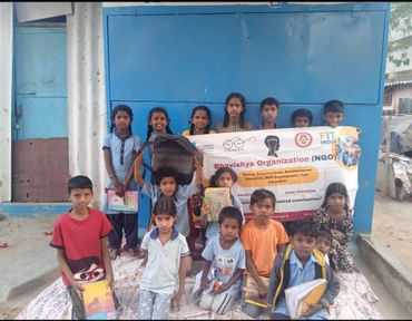 Group of children holding educational materials with an NGO banner in the background.