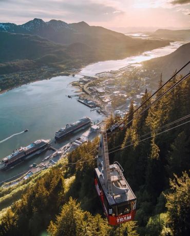 A tram ascending a mountain overlooking a river and town.