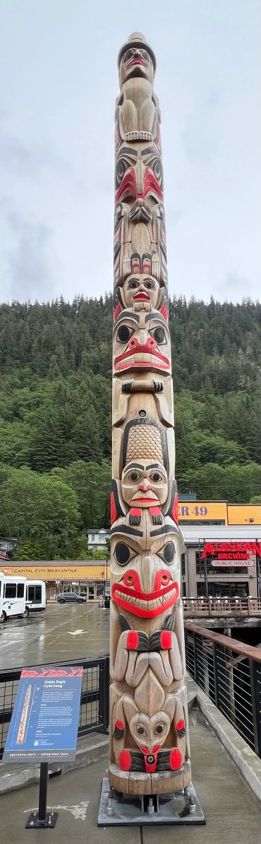 Tall Native American totem pole with intricate carvings and bright colors.