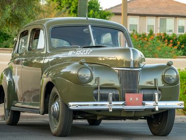 Classic vintage olive green car parked outdoors.