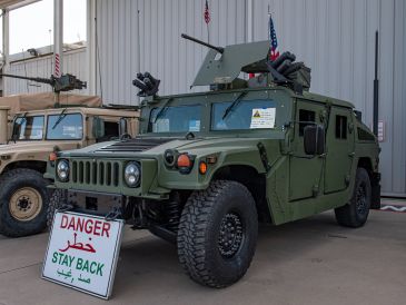 Military green armored vehicle with mounted weapons.