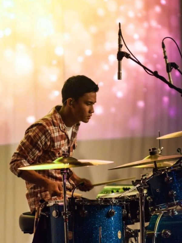 A focused drummer playing drums on stage.
