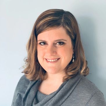 Portrait of a smiling woman with shoulder-length hair against a light background.