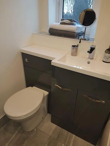 Modern bathroom with dark gray cabinets, white sink, and toilet.