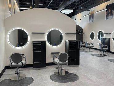 Modern hair salon with sleek styling stations and illuminated mirrors.