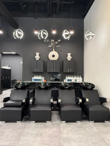 Modern salon washing stations with black chairs and sinks.