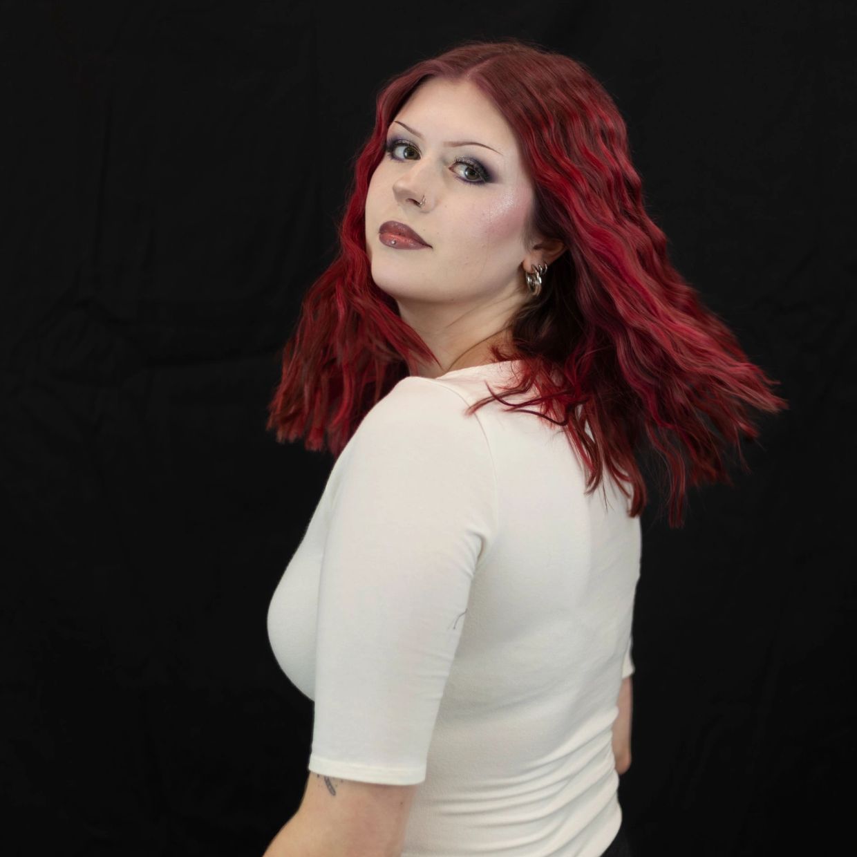 Woman with red hair posing against a black background.
