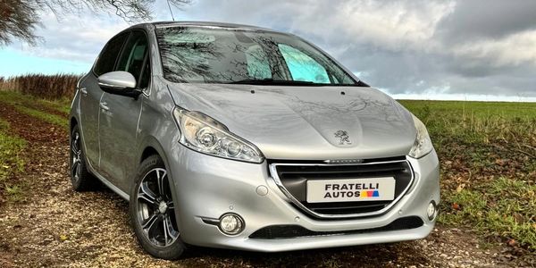 Silver Peugeot car parked on a gravel path with a cloudy sky.