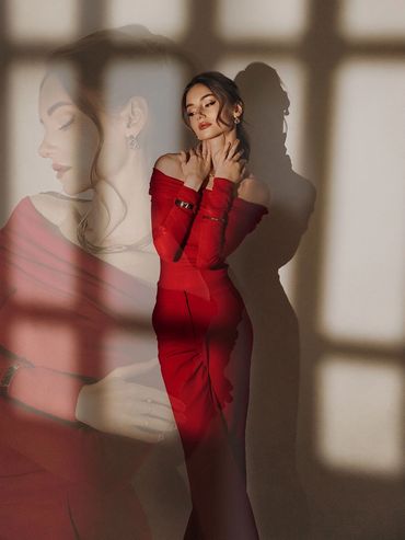 Woman in red dress posing with a shadow and reflection.