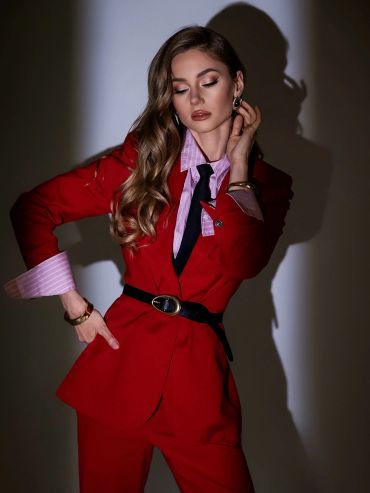 Woman in a stylish red suit with long wavy hair.