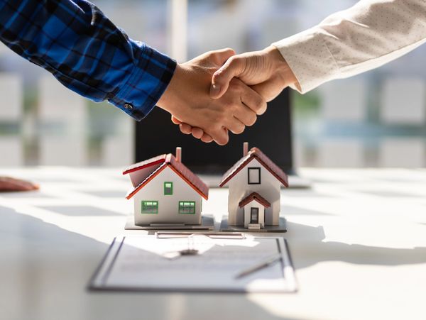 Real estate agents shake hands after the signing of the contract agreement is complete.