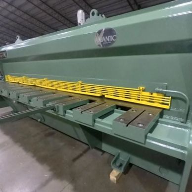 Large green industrial sheet metal shear machine.