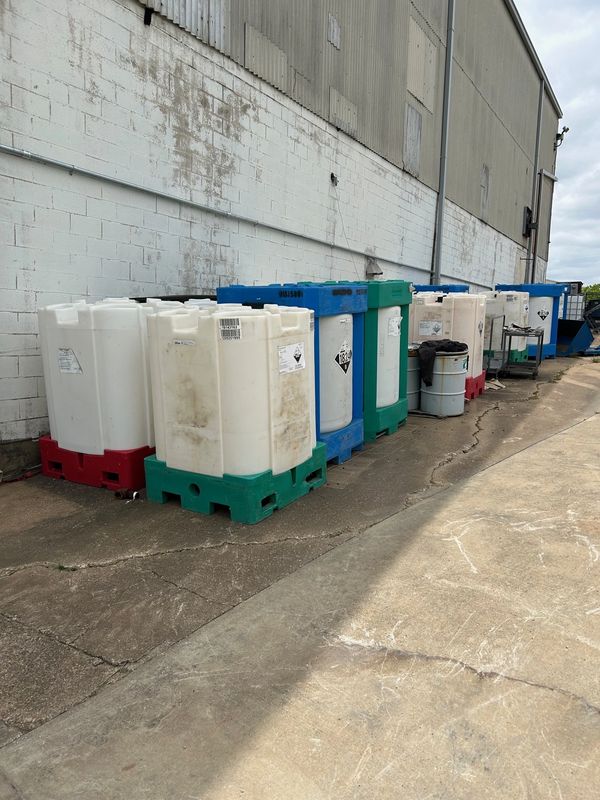 Large chemical containers lined up outside a building.