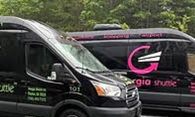 Two black vans with 'gia shuttle' branding parked outdoors.