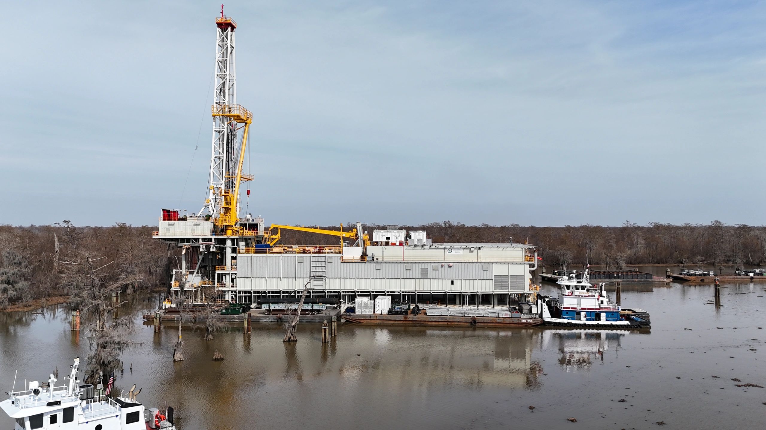 Oil drilling rig on a river barge in a swampy area.
