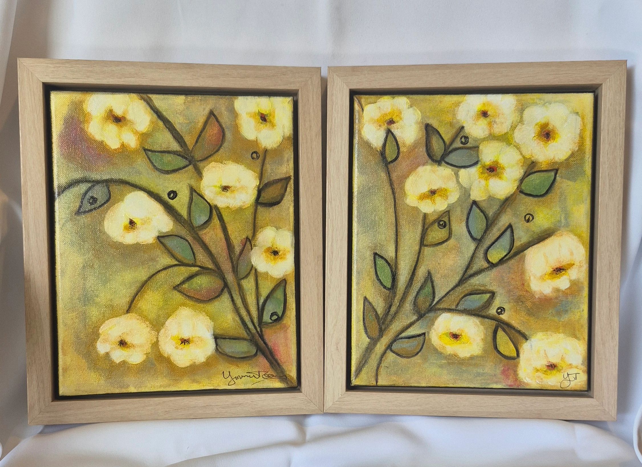 Two framed floral paintings with yellow flowers and green leaves.