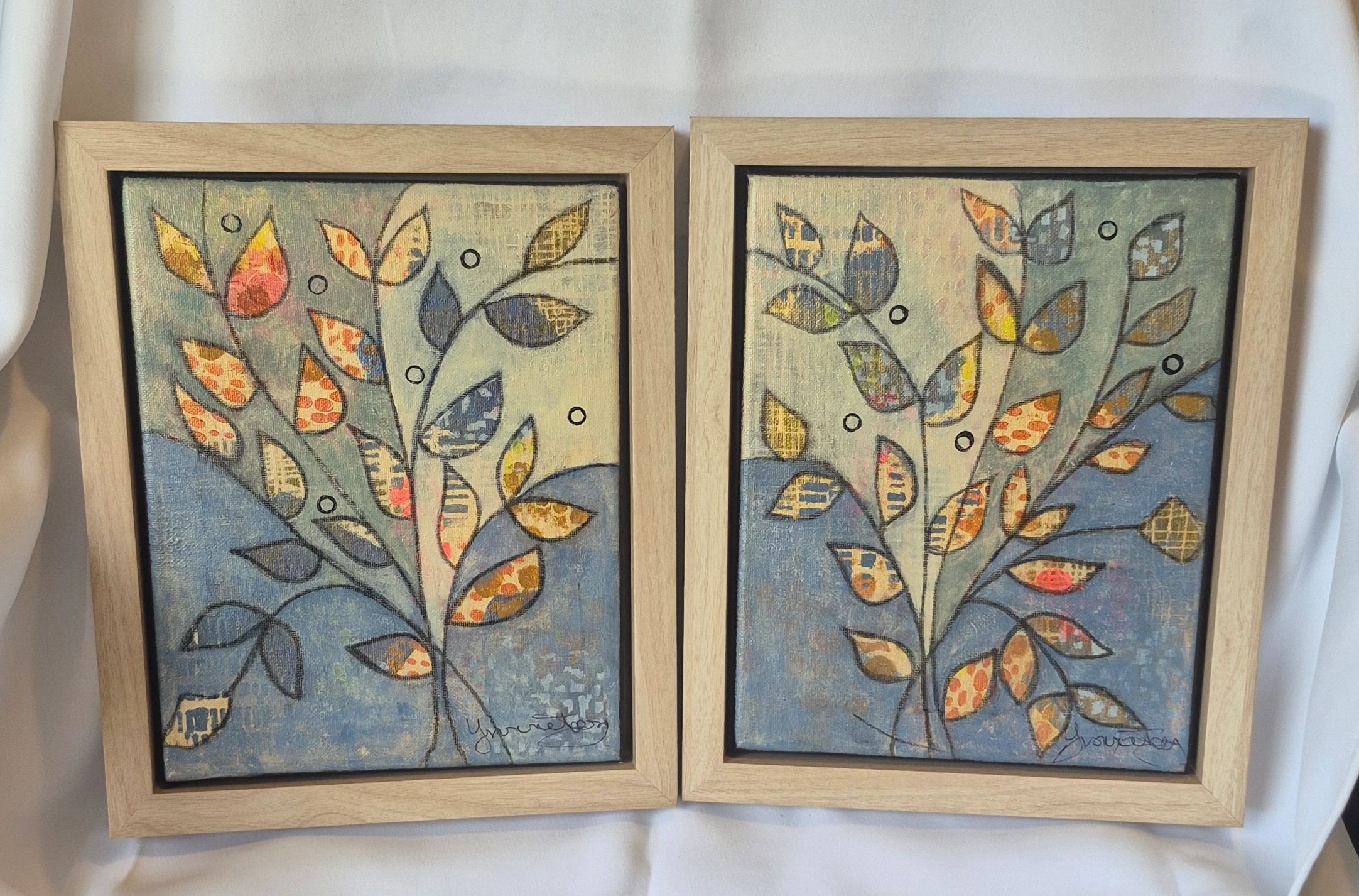 Two framed colorful leaf paintings side by side.