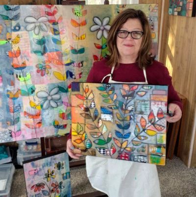 Contemplative artist in her studio, surrounded by her floral creations.