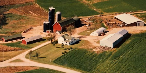 Aerial view of a farm with silos, barns, and green fields.