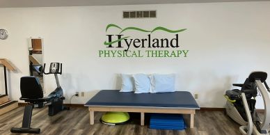 Physical therapy room with exercise equipment and treatment table.