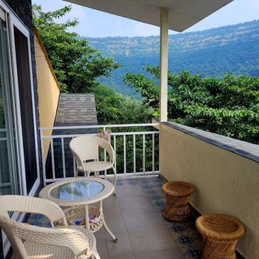 Cozy balcony with wicker furniture overlooking lush green hills.