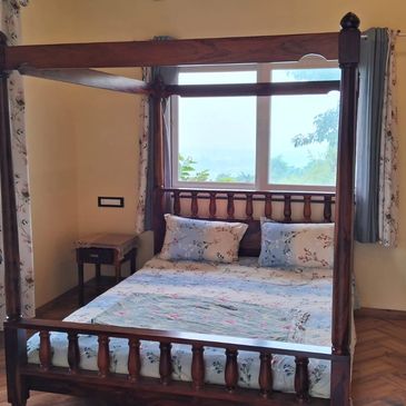 Cozy wooden four-poster bed with floral bedding in a bright room.