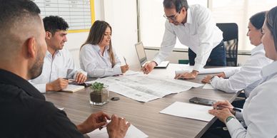 Team discusses CPG sales forecasts, distribution plans, and timelines around charts and whiteboard.