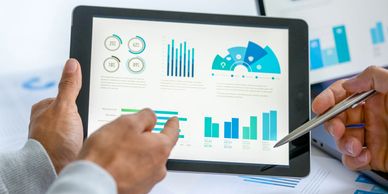 Two business people meeting and looking at financial data, charts and graphs on a digital tablet. 