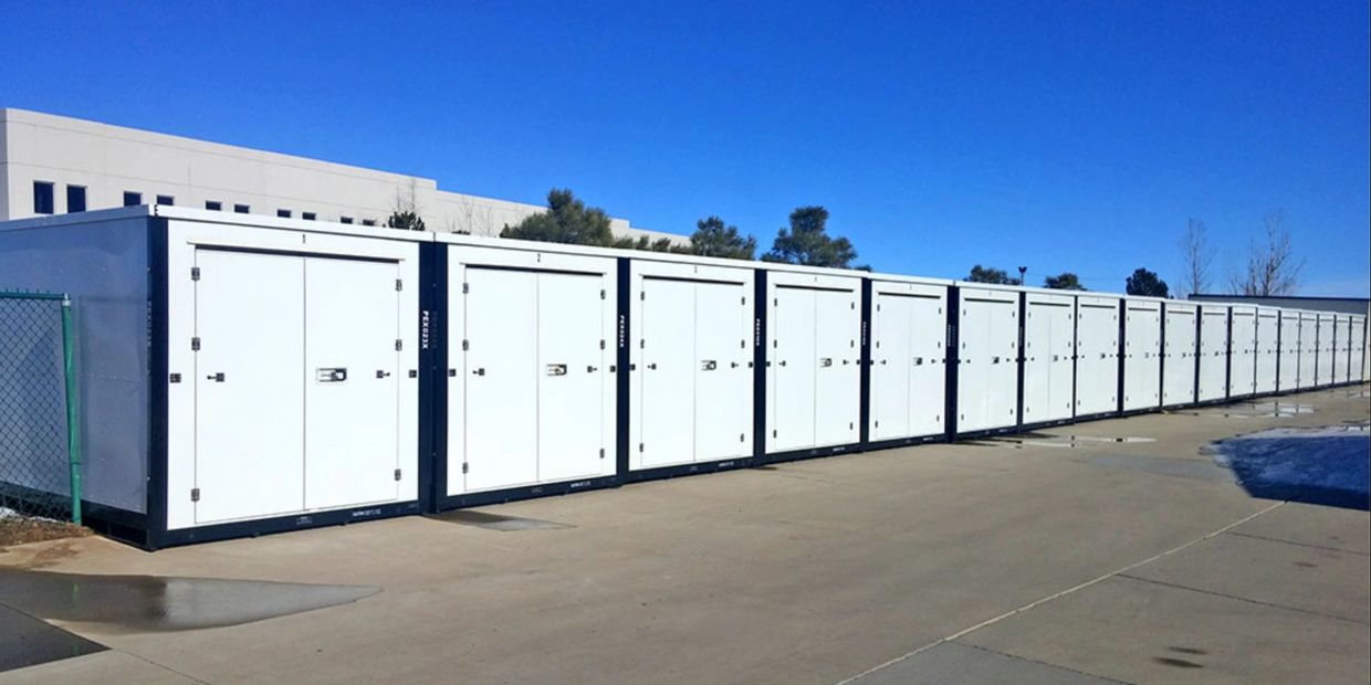 A long row of white storage containers under a clear blue sky.