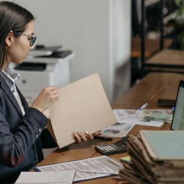 Woman reviewing documents at a cluttered office desk.