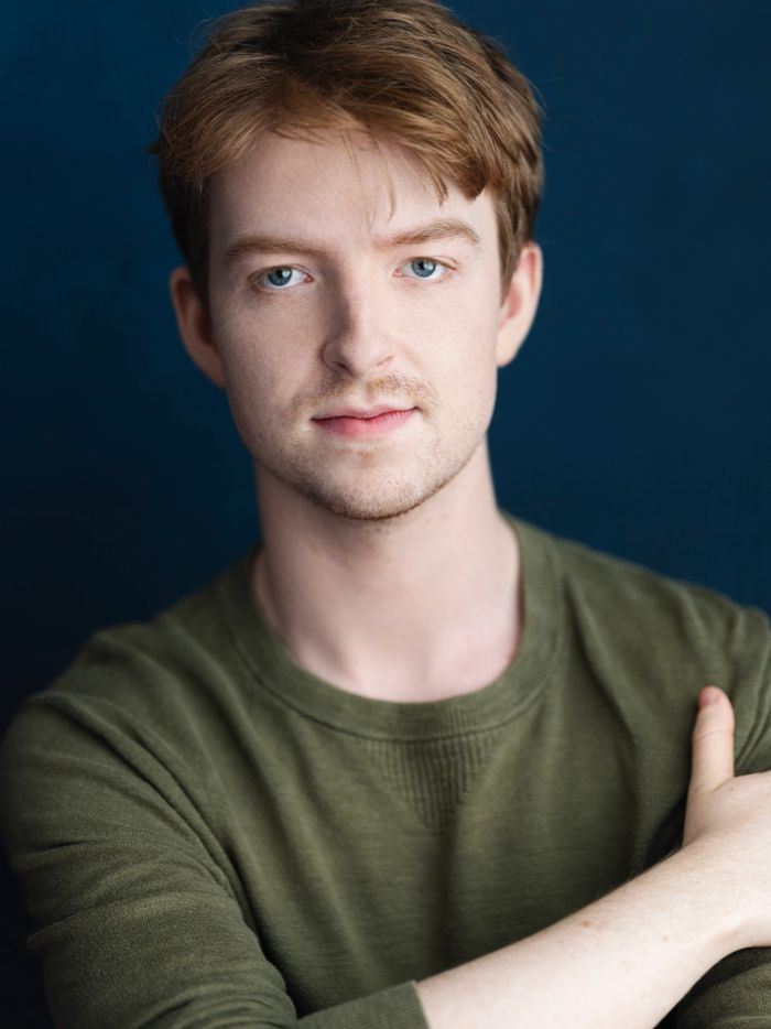 Stack of books next to pencils in a holder and a camera.