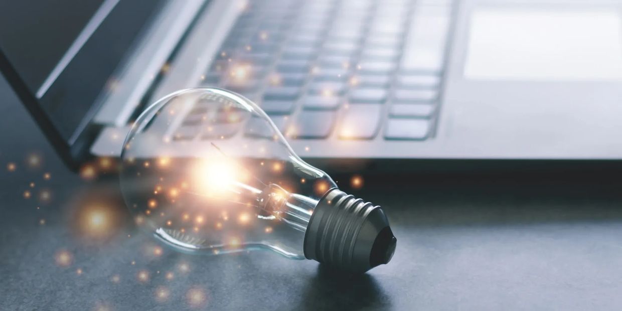 Image of a light bulb near a laptop/keyboard. 