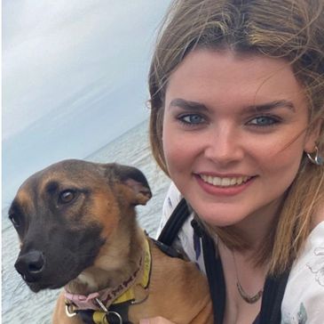 Lady holding a dog at the beach providing small animal and dog walking services around Cheshire.