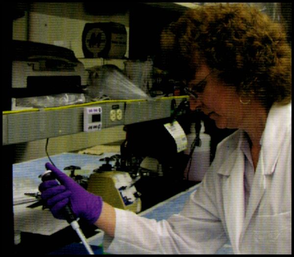 Scientist in a lab coat using a pipette in a laboratory setting.