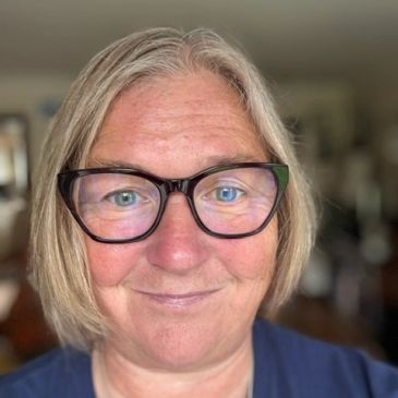 Smiling woman with glasses and gray hair.