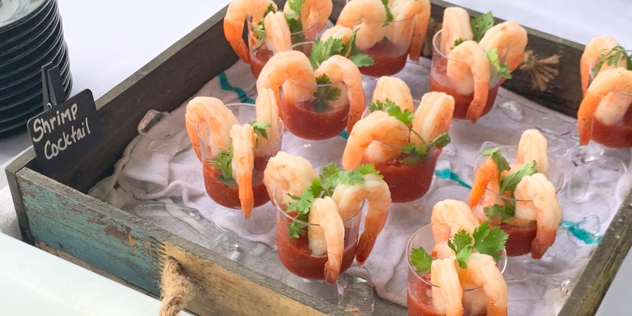 Shrimp cocktails served in individual cups with cocktail sauce and garnish.