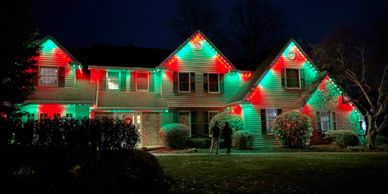 A house decorated with red and green Christmas lights at night.