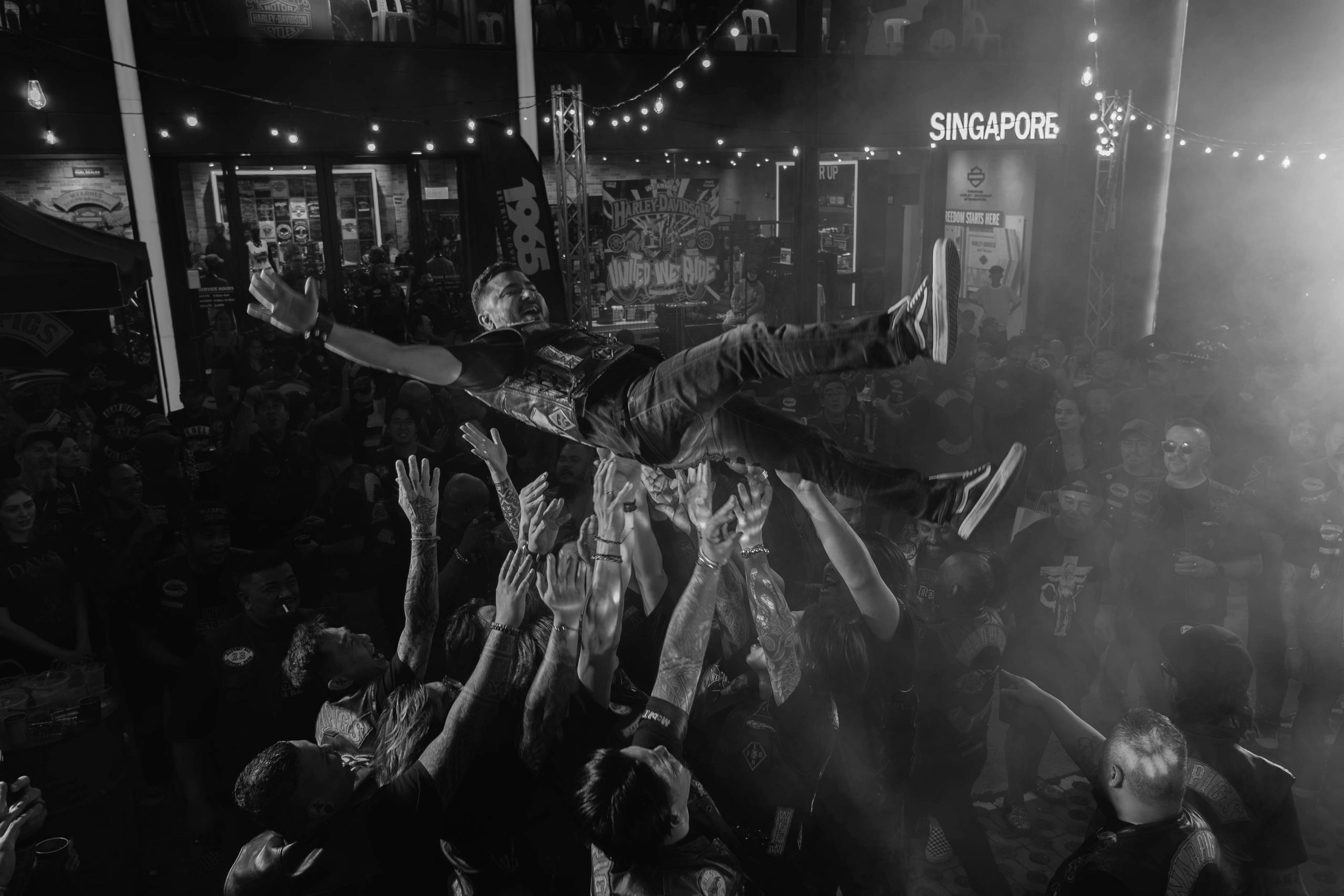 A man crowd surfing at a lively night event in Singapore.