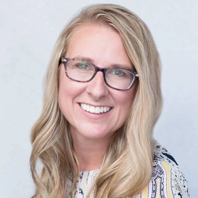 Smiling woman with glasses and long blonde hair.