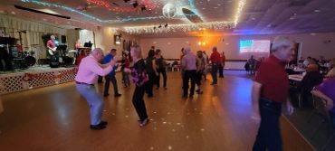 People dancing in a decorated hall with stage and disco lights.